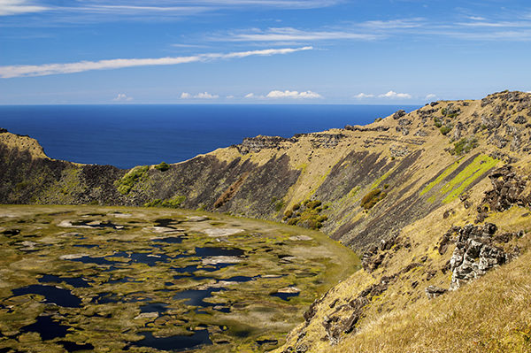 Rano Kau, an extinct volcanic crater at Easter Island, Chile, filled with green algae. The Pacific Ocean is in the background.