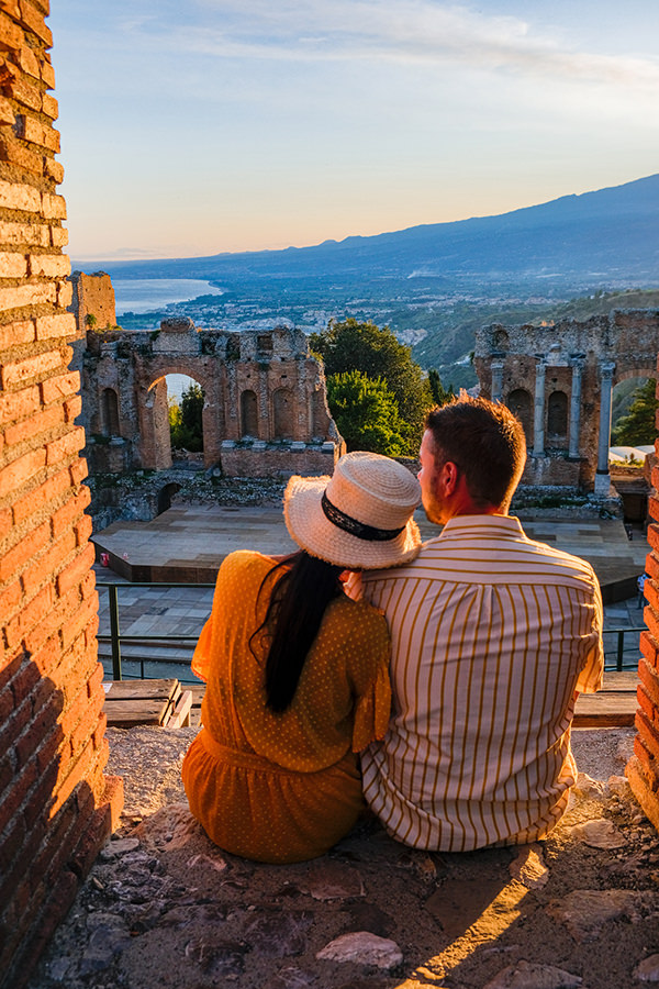 Taormina Sicily, couple watching sunset at the Ruins of the Ancient Greek Theater in Taormina, Sicily. couple mid age on vacation Sicilia