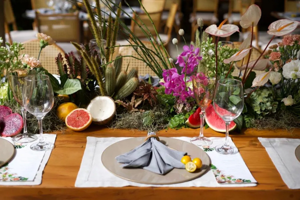 sousplast do Casamento de Camilla de Lucas e Mateus Ricardo, mesa decorada com frutas, sousplast cinza e marrom claro, flores rosas e brancas ao fundo 