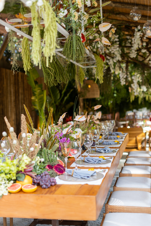 Casamento de Camilla de Lucas e Mateus Ricardo, decoração da mesa dos convidados, mesa enfeitada com frutas, plantas posicionadas no teto, diferentes tipos de planta e flores