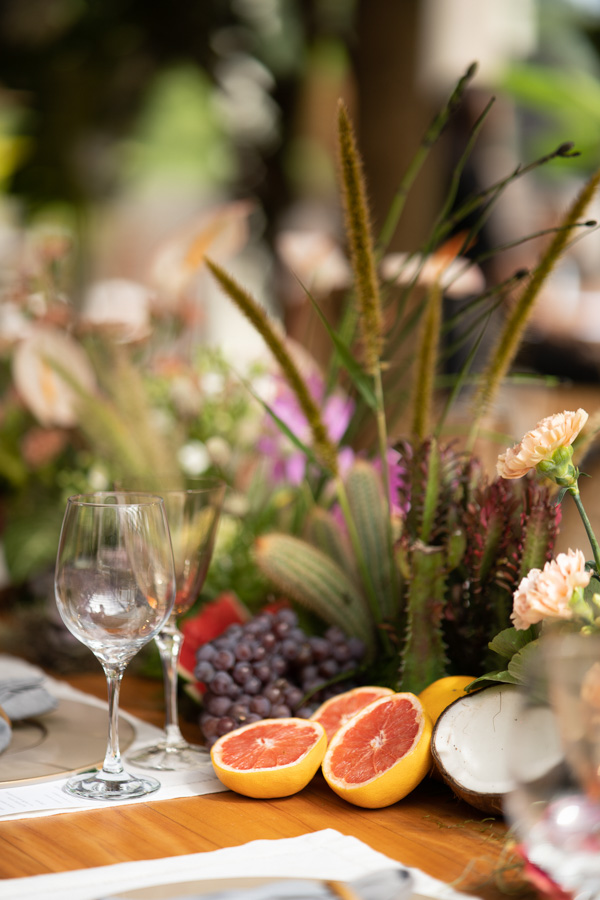 Casamento de Camilla de Lucas e Mateus Ricardo, decoração com foco nas frutas laranja, uva e flores, taças em cima da mesa