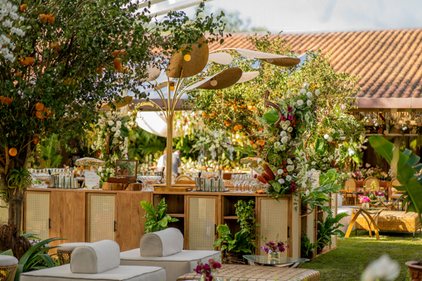 Decoração do casamento de Camilla de Lucas e Mateus Ricardo, espaço externo com imobiliários brancos, flores roxas, pé de laranjas, flores brancas e folhas espalhadas pelo local 