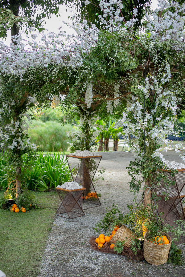 espaço externo do casamento de Camilla de Lucas e Mateus Ricardo, passarela dos noivos enfeitadas com flores brancas e frutas de laranjas ao chão