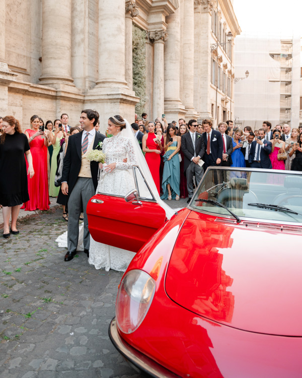 casamento de Sabine Arias, destination wedding na Itália, casamento em Roma, casamento na igreja, noivos saindo da igreja, noivos no carro, carro vermelho, saida da igreja